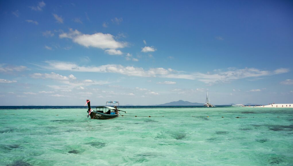 old wooden longtail boat on crystal clear water