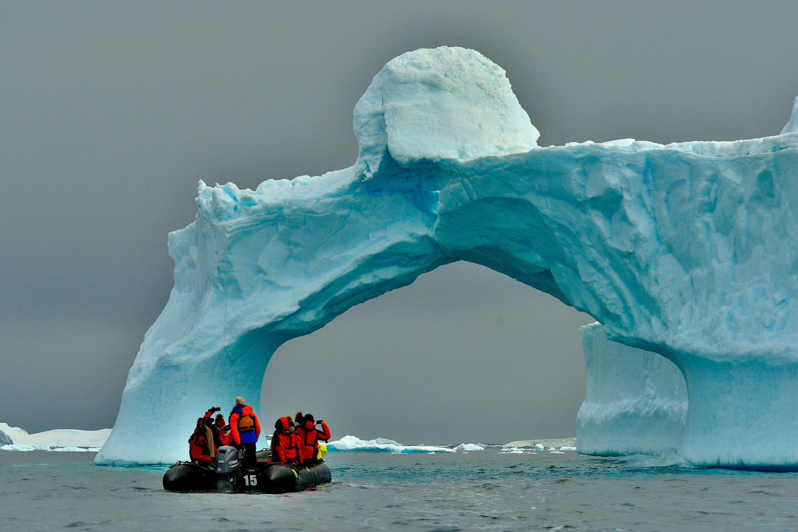 guys dressed in red on a boat next to icebergs