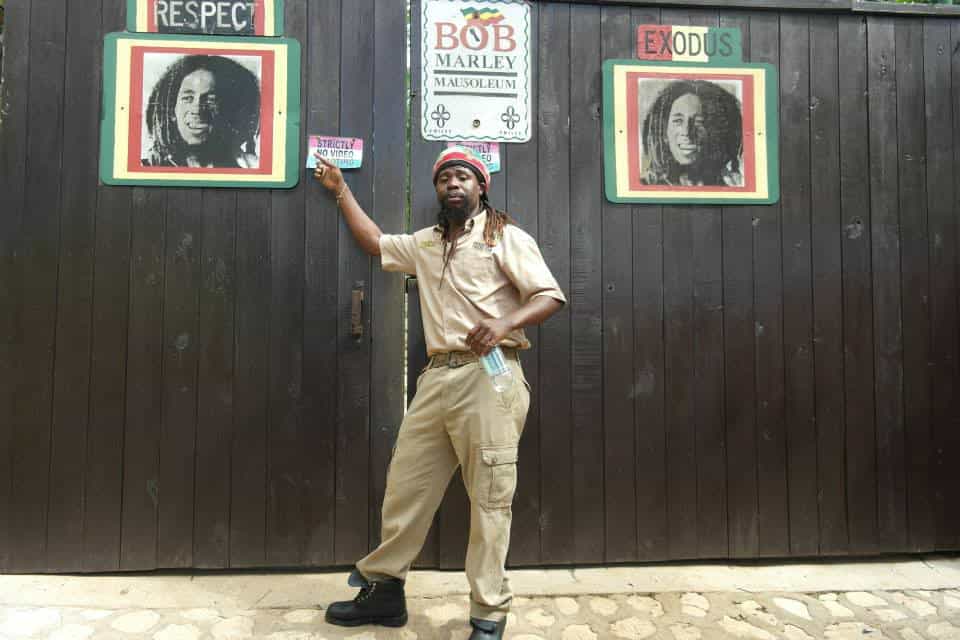 a guy in white pointing at a poster on a black wall
