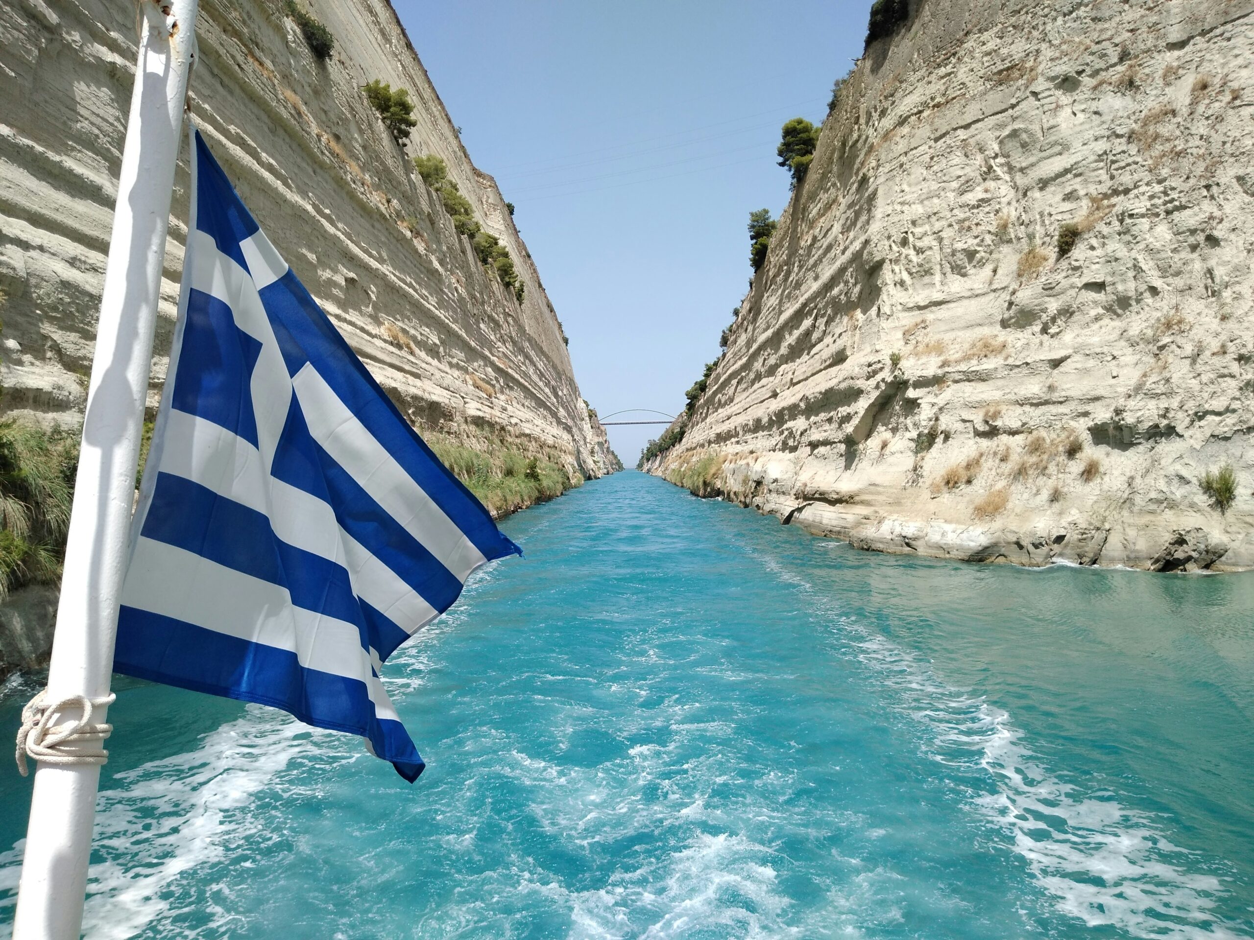 blue water with vertical cliffs and a blue and white flag
