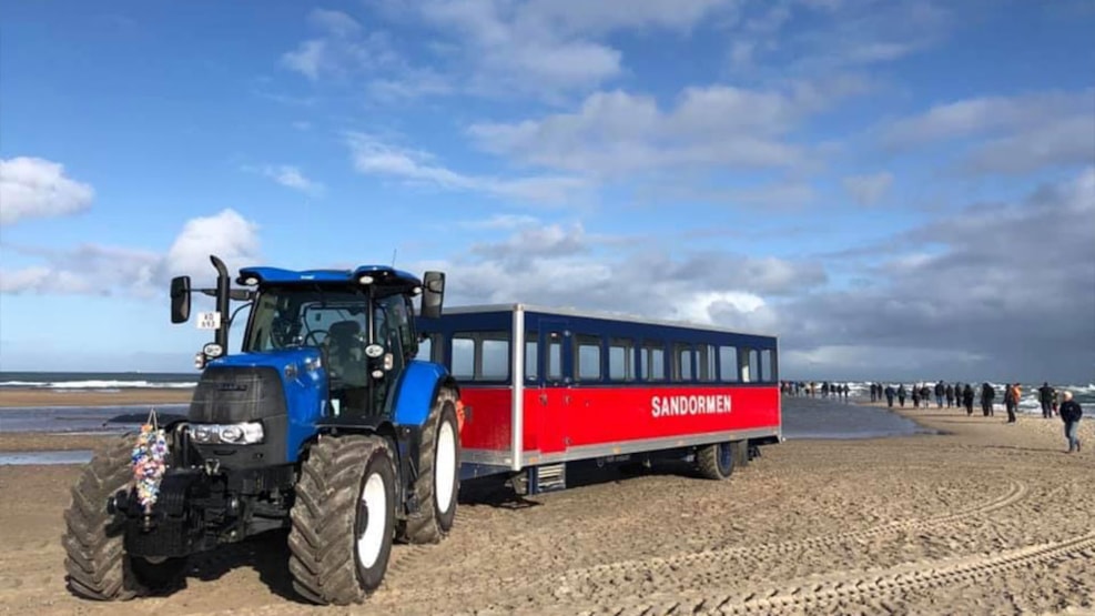 a blue tractor pulling a red carriage