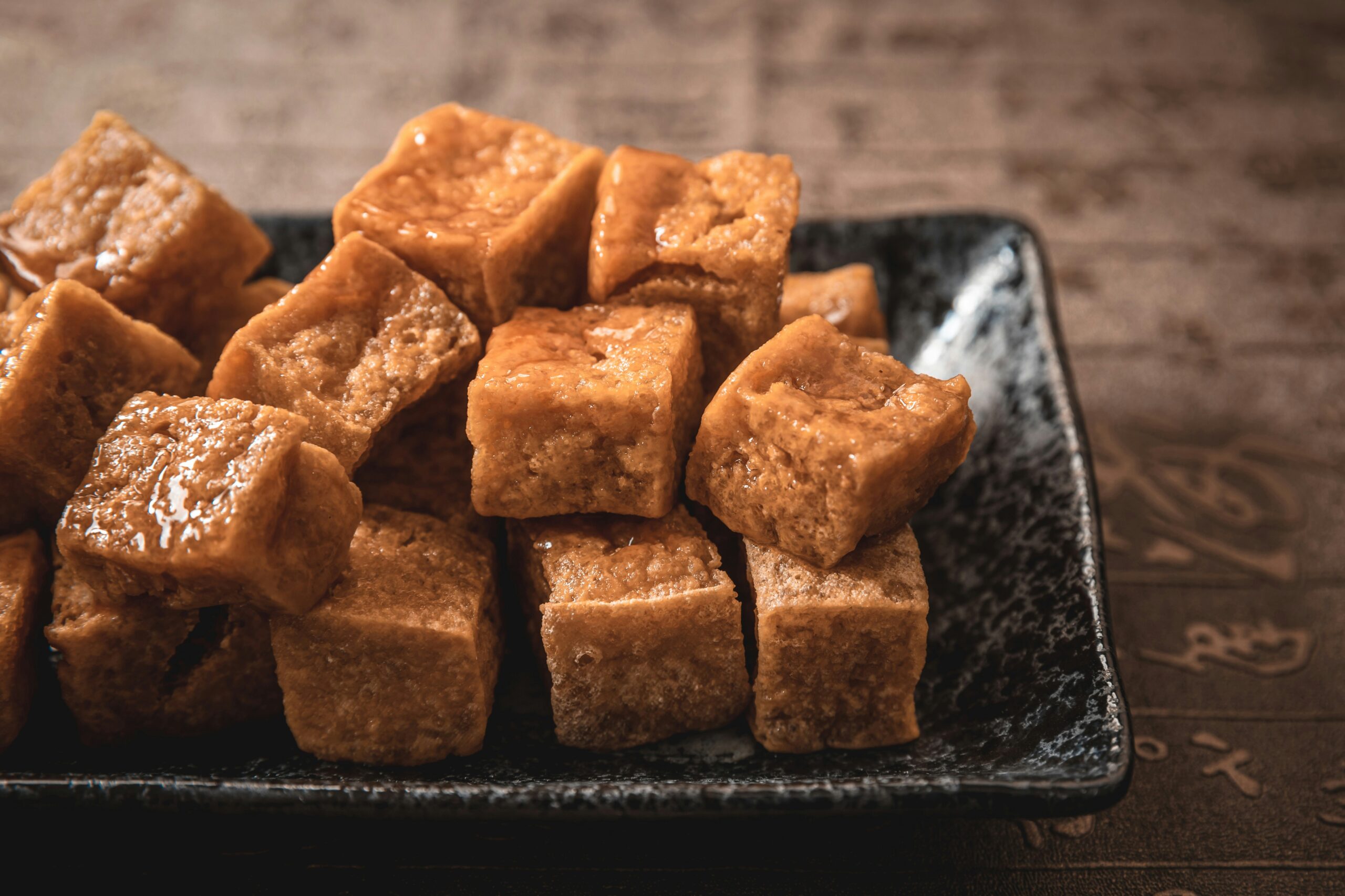 a pile of cooked tofu on a black plate