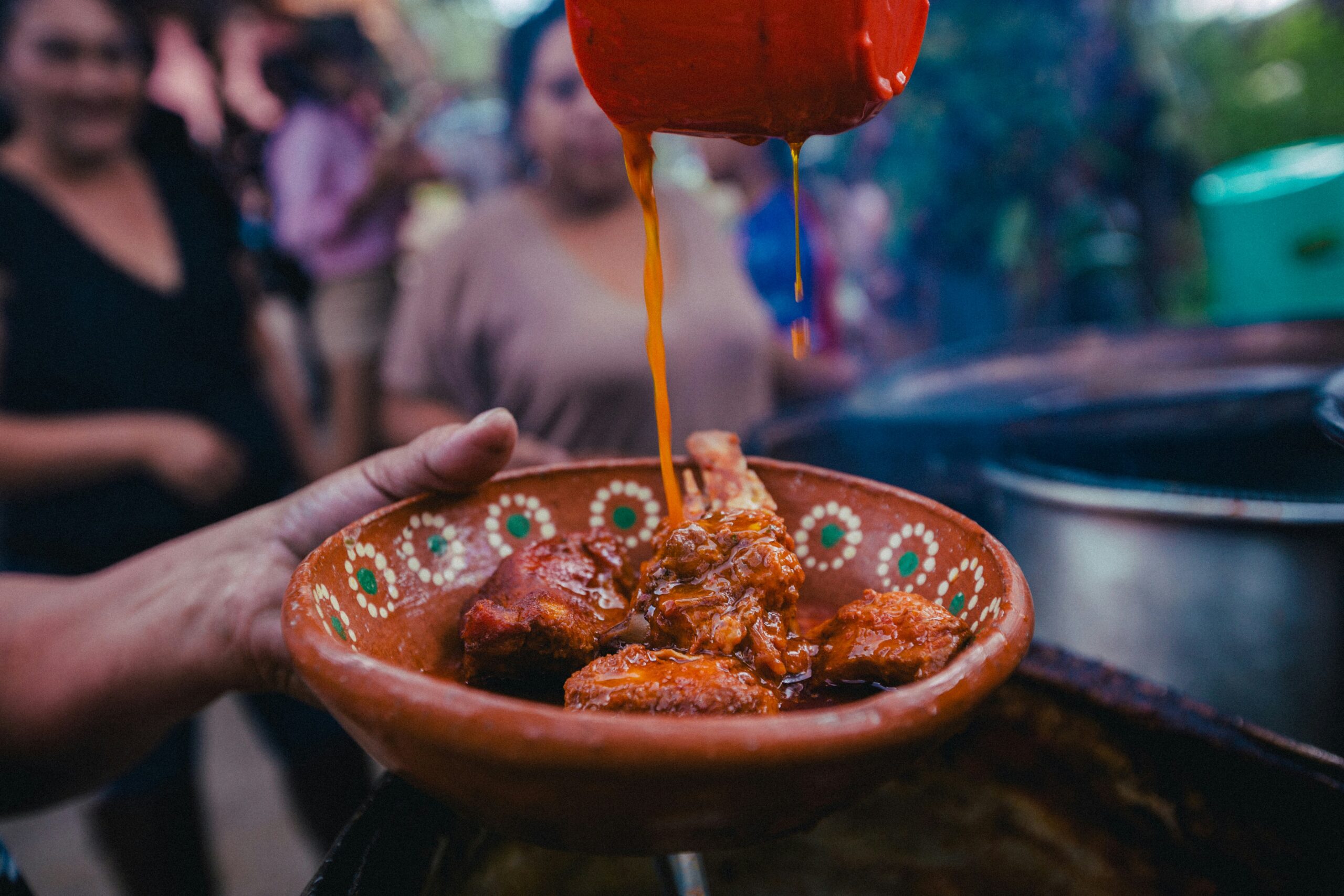 pouring sauce over a bowl of food