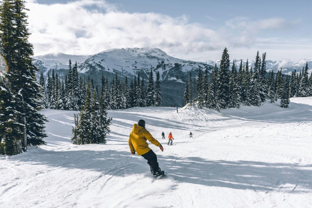 a guy in a yellow ski jacket skiing down a slope