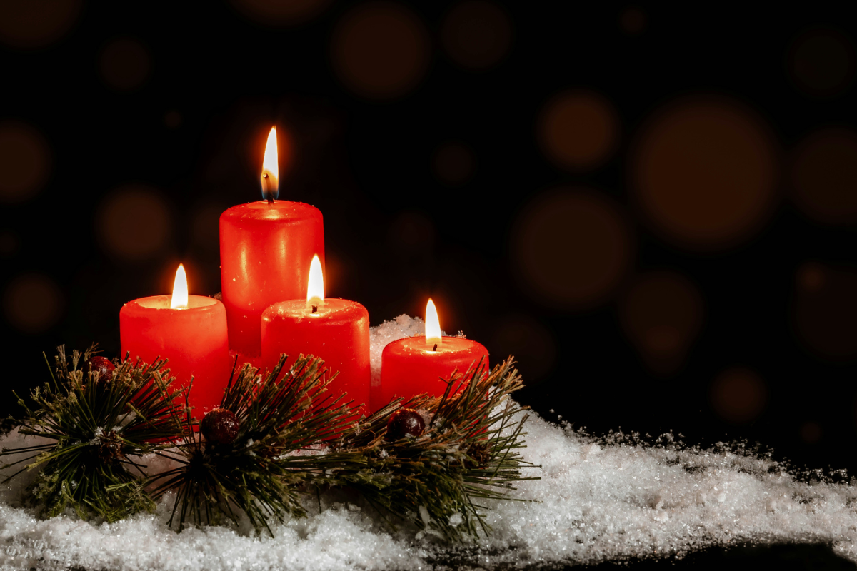 four red candles burning in the snow