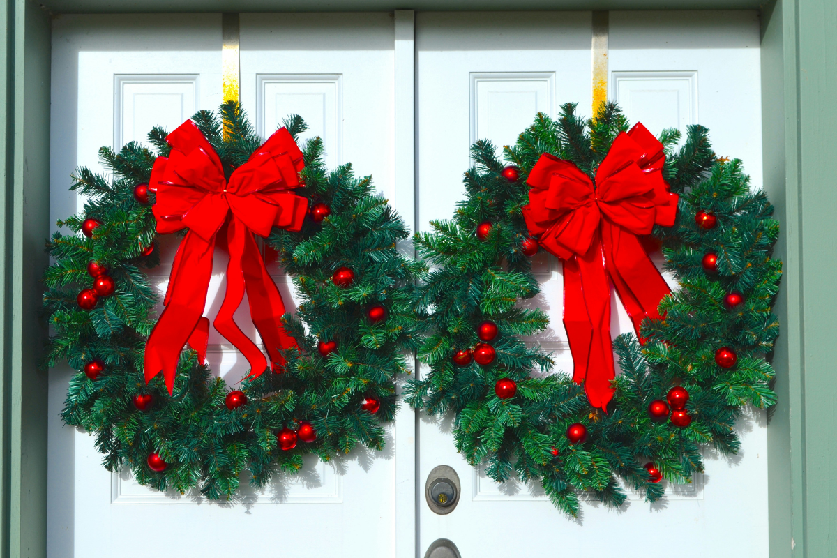 christmas wreath hanging on two white doors